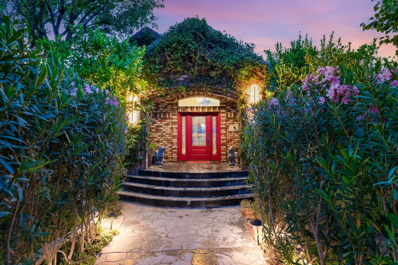 Stone-arched entry and red front door at dusk