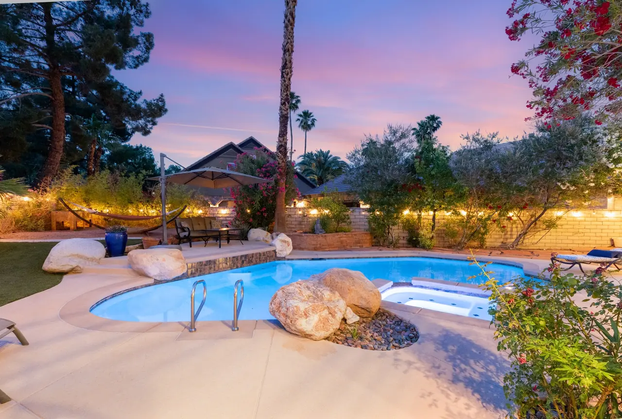Free-form pool with boulders and lit palms at dusk